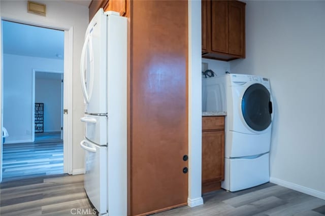 washroom featuring washer / clothes dryer, baseboards, and light wood finished floors