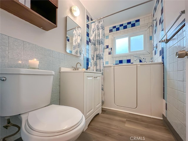 full bath featuring curtained shower, toilet, wood finished floors, vanity, and tile walls