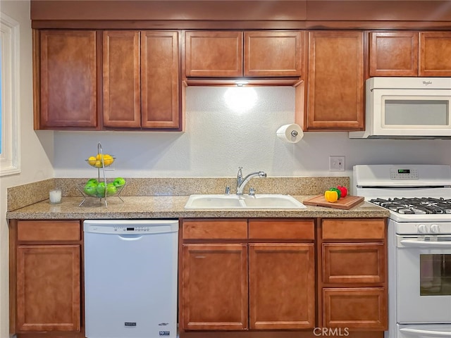 kitchen with white appliances, light countertops, a sink, and brown cabinetry