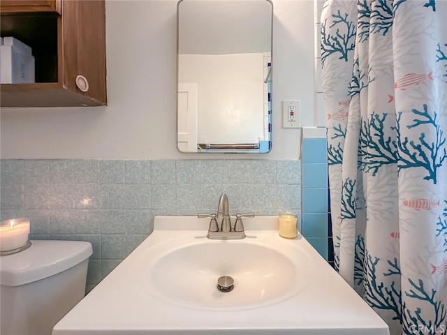 full bath with toilet, tile walls, and vanity