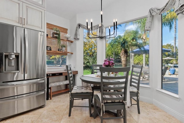 dining area with a notable chandelier, a healthy amount of sunlight, baseboards, and light tile patterned floors