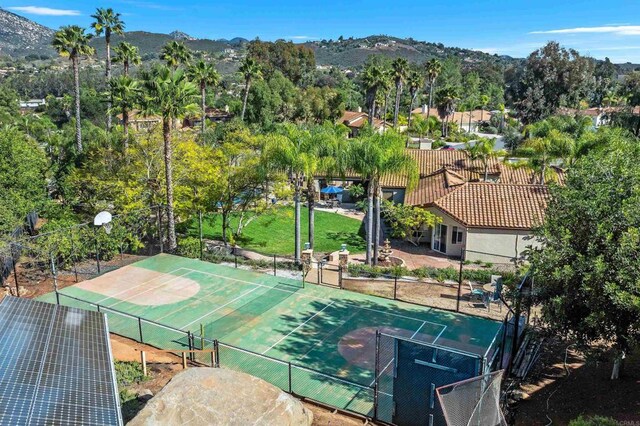 view of sport court featuring community basketball court, a gate, fence, and a mountain view