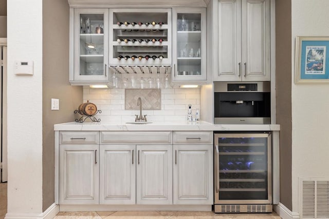 bar featuring wine cooler, a sink, wet bar, and tasteful backsplash