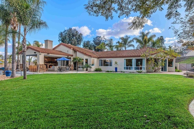 rear view of house with a tile roof, a patio area, a lawn, and stucco siding