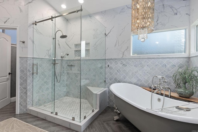 full bathroom with a shower stall, a freestanding tub, and tile walls