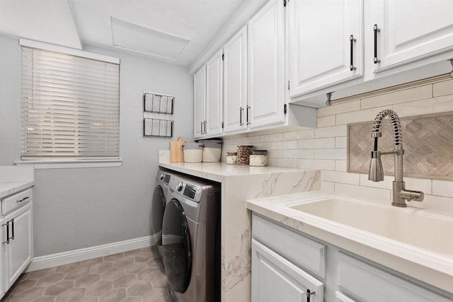 washroom featuring baseboards, attic access, cabinet space, a sink, and washing machine and dryer