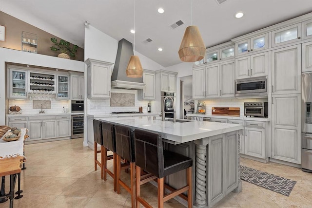 kitchen with beverage cooler, visible vents, appliances with stainless steel finishes, a kitchen bar, and wall chimney range hood