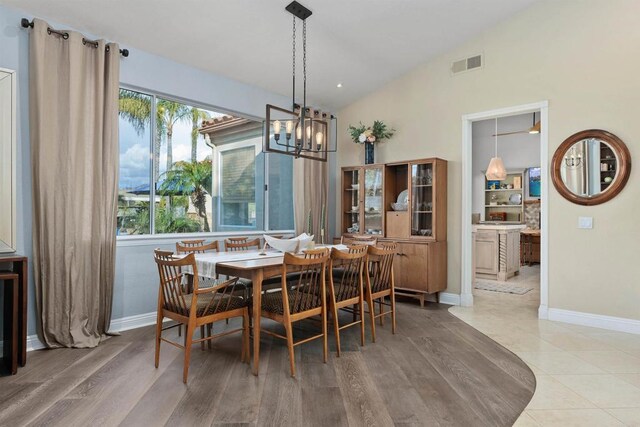 dining space featuring visible vents, lofted ceiling, an inviting chandelier, and wood finished floors