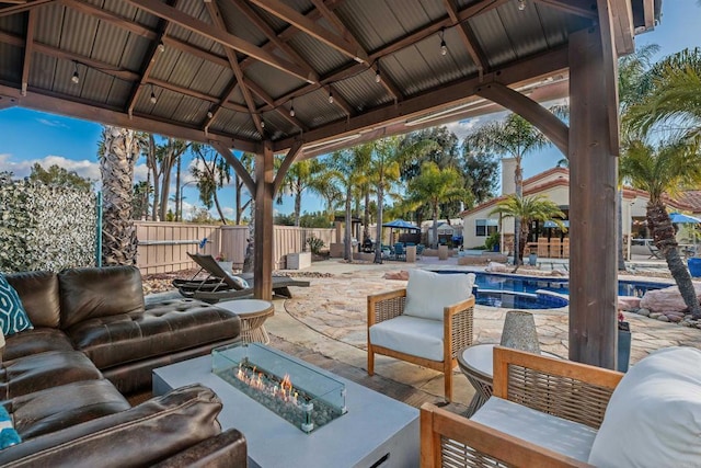 view of patio / terrace with an outdoor living space with a fire pit, a gazebo, fence, and an outdoor pool