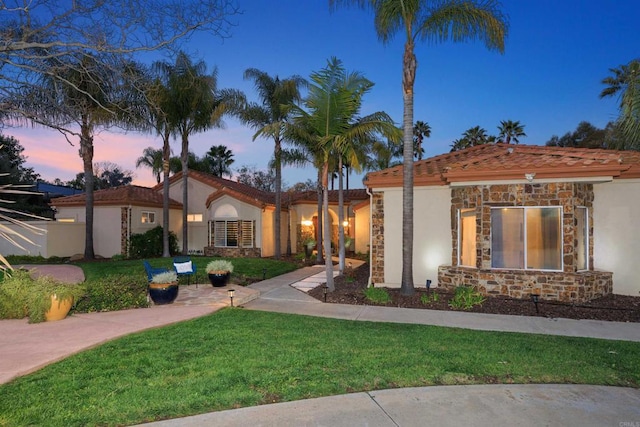 view of front of house with stucco siding, stone siding, and a front yard