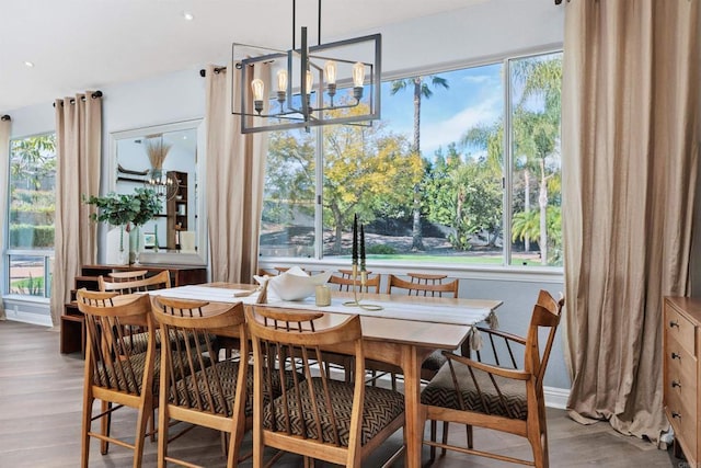 dining space featuring a notable chandelier, plenty of natural light, wood finished floors, and baseboards