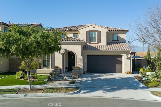 mediterranean / spanish-style home with fence, a tiled roof, concrete driveway, stucco siding, and an attached garage