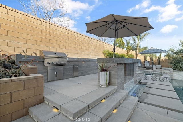 view of patio featuring a fenced backyard, area for grilling, and exterior kitchen