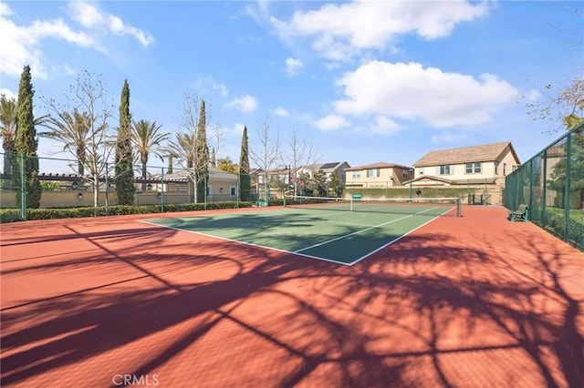 view of tennis court with a residential view and fence