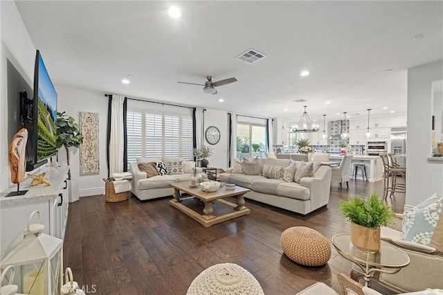 living area featuring recessed lighting, visible vents, dark wood finished floors, and ceiling fan with notable chandelier