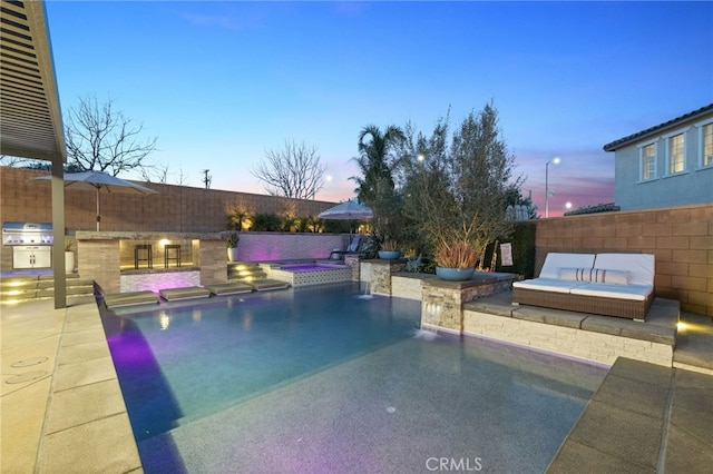 view of swimming pool with area for grilling, a patio, a fenced backyard, exterior kitchen, and an in ground hot tub