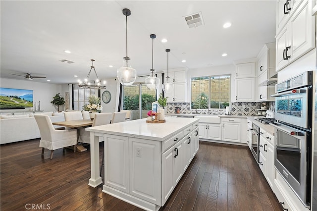 kitchen with visible vents, decorative backsplash, white cabinetry, double oven, and open floor plan