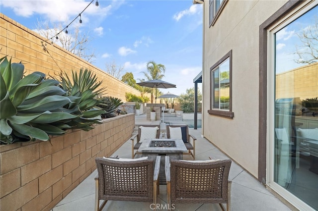 view of patio with an outdoor living space with a fire pit and fence