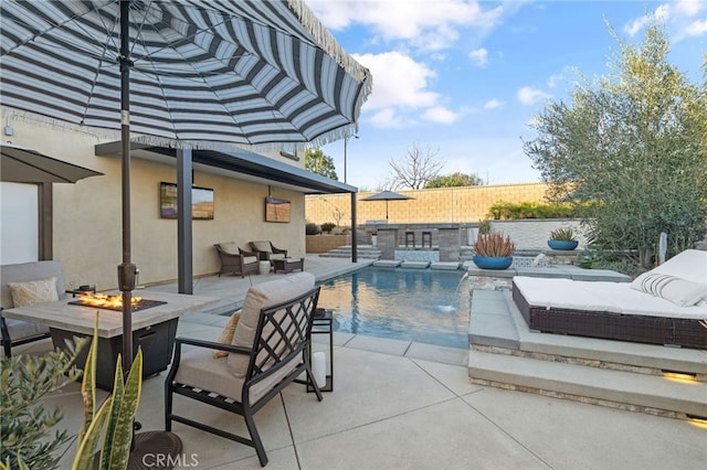 view of pool featuring area for grilling, outdoor dry bar, fence, an outdoor living space with a fire pit, and a patio area