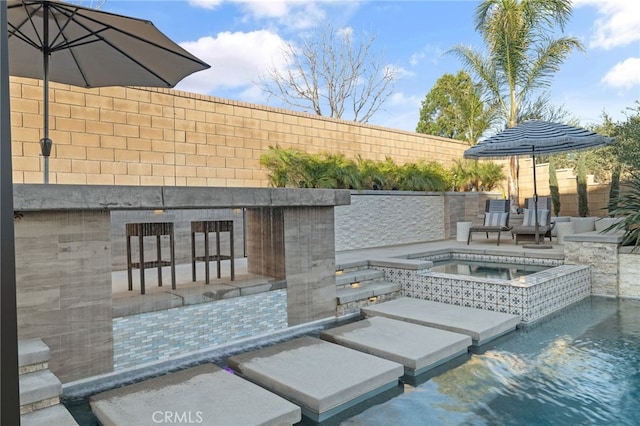 view of patio / terrace featuring an in ground hot tub and fence