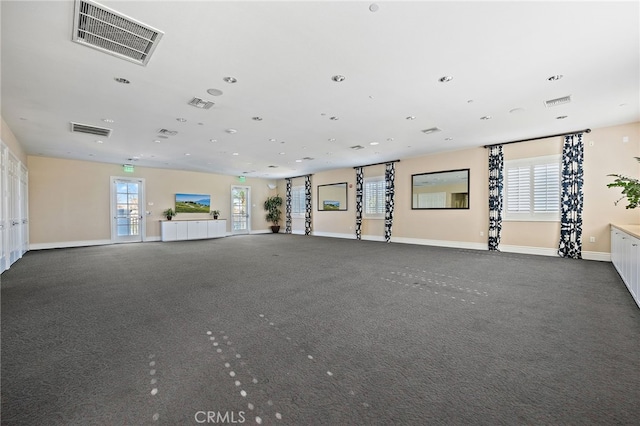 unfurnished living room with visible vents, plenty of natural light, and baseboards