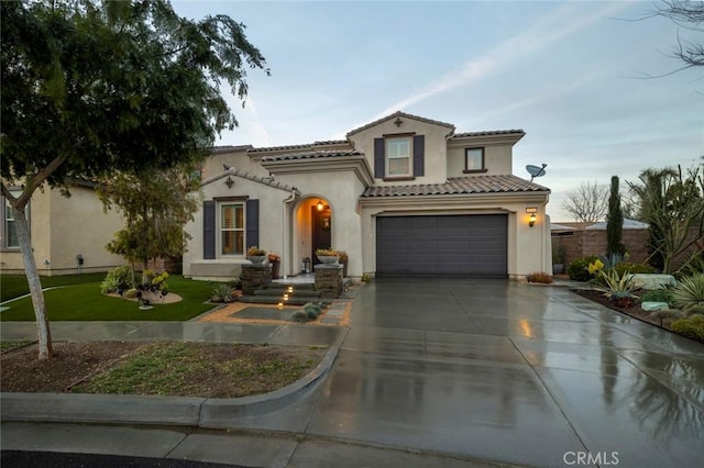 mediterranean / spanish house featuring concrete driveway, an attached garage, a tile roof, and stucco siding