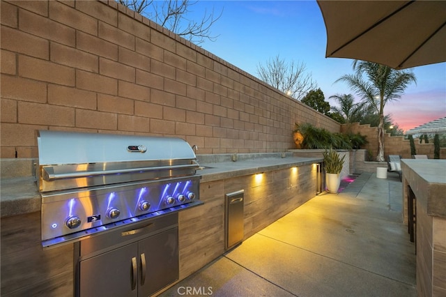 view of patio with an outdoor kitchen, a fenced backyard, and a grill