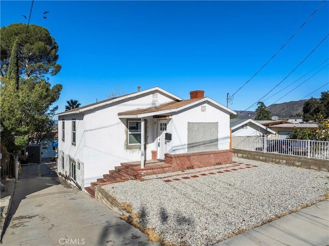 view of front of property featuring a chimney, fence, and stucco siding