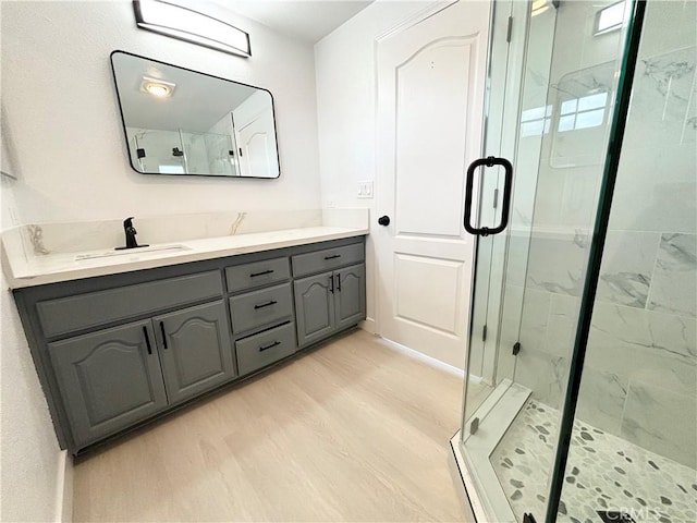 bathroom featuring vanity, a marble finish shower, and wood finished floors