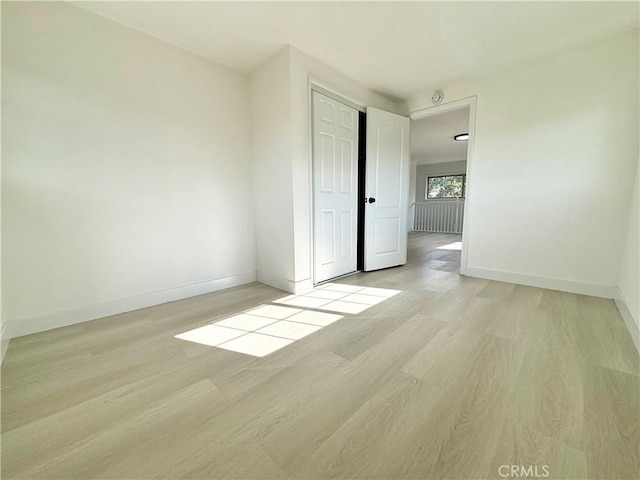 empty room with light wood finished floors and baseboards