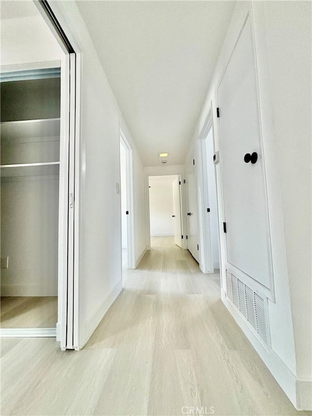 corridor with light wood-type flooring, baseboards, and visible vents