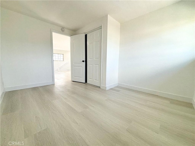 spare room featuring baseboards and light wood-style floors