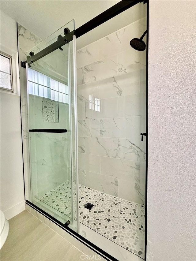 full bath with a stall shower, wood finished floors, and baseboards