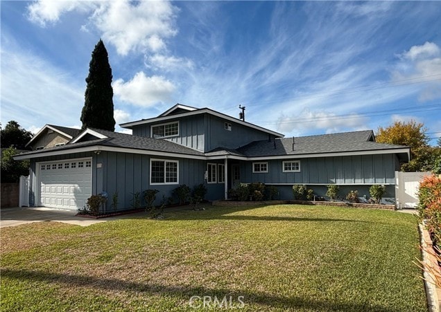 view of front of house with a garage, driveway, fence, board and batten siding, and a front yard