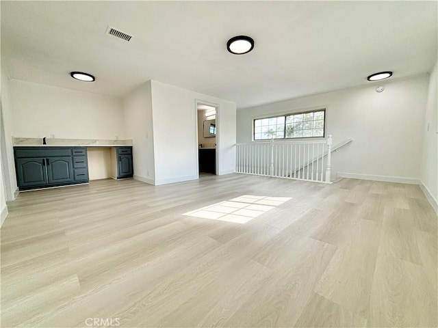 unfurnished living room with light wood-type flooring, baseboards, and visible vents