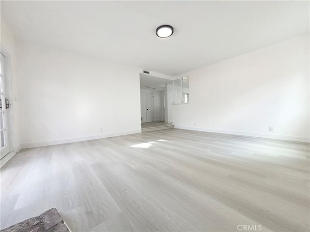 unfurnished room with light wood-type flooring and baseboards