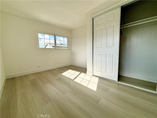 unfurnished bedroom with a closet, baseboards, and wood finished floors