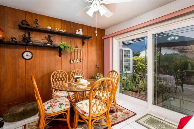 dining area with wood walls and ceiling fan