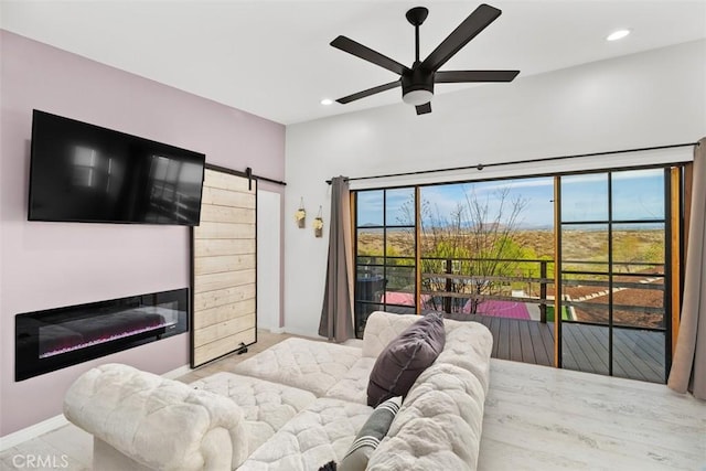 bedroom with a ceiling fan, recessed lighting, access to exterior, a glass covered fireplace, and a barn door