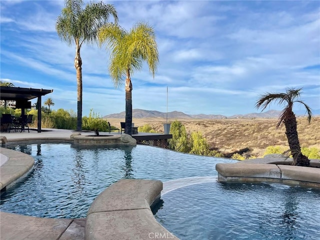 view of swimming pool featuring a patio area, a mountain view, and a pool with connected hot tub