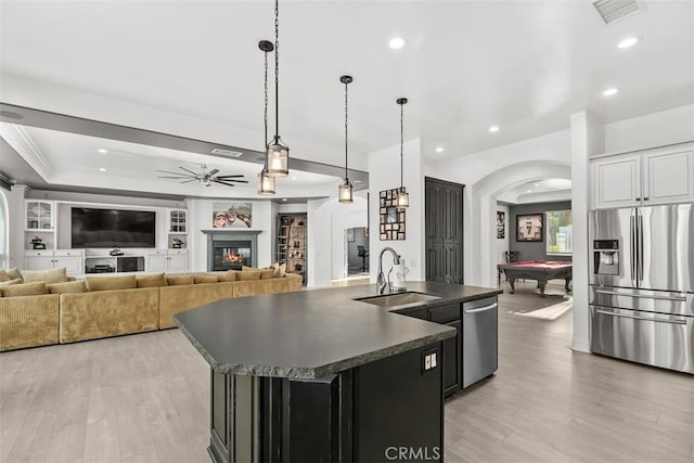 kitchen featuring visible vents, a sink, dark countertops, stainless steel appliances, and arched walkways