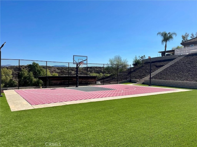 view of basketball court featuring a lawn, community basketball court, and fence