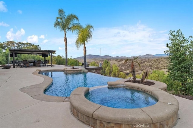 view of swimming pool with outdoor dining space, a patio, a mountain view, and a pool with connected hot tub