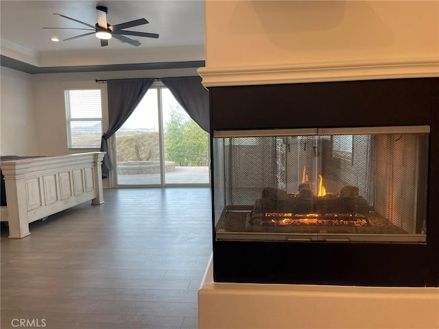 unfurnished bedroom with a multi sided fireplace, ornamental molding, recessed lighting, wood finished floors, and access to outside