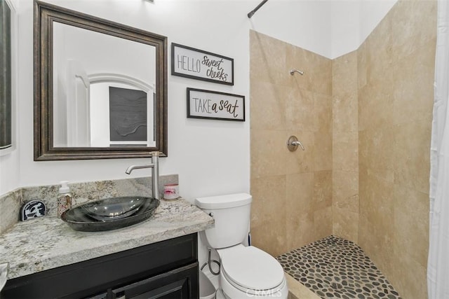 bathroom with tiled shower, toilet, and vanity