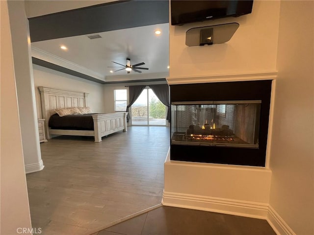 unfurnished bedroom with wood finished floors, baseboards, recessed lighting, a multi sided fireplace, and ornamental molding