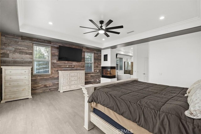 bedroom featuring visible vents, wood finished floors, a multi sided fireplace, and ornamental molding