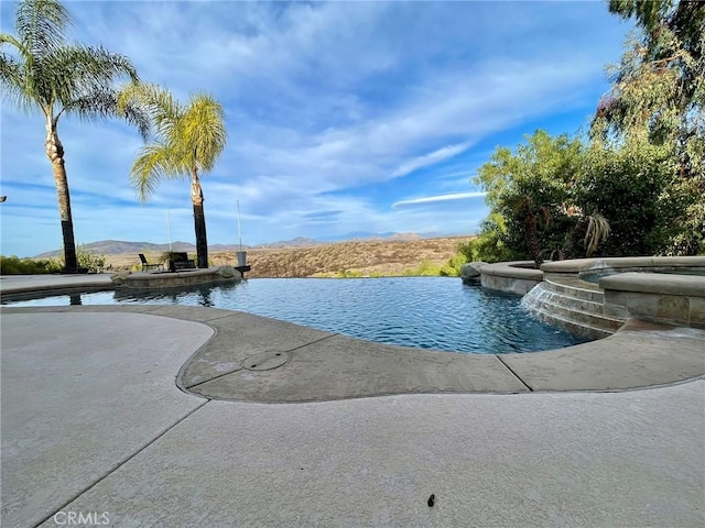 view of swimming pool with a patio and a pool with connected hot tub