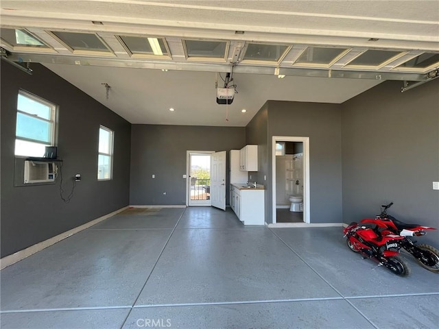 garage with cooling unit, a garage door opener, baseboards, and a sink