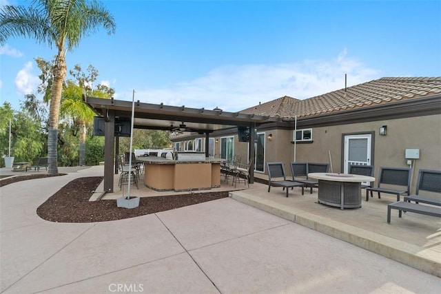 view of patio / terrace with outdoor dry bar, ceiling fan, an outdoor fire pit, and central AC